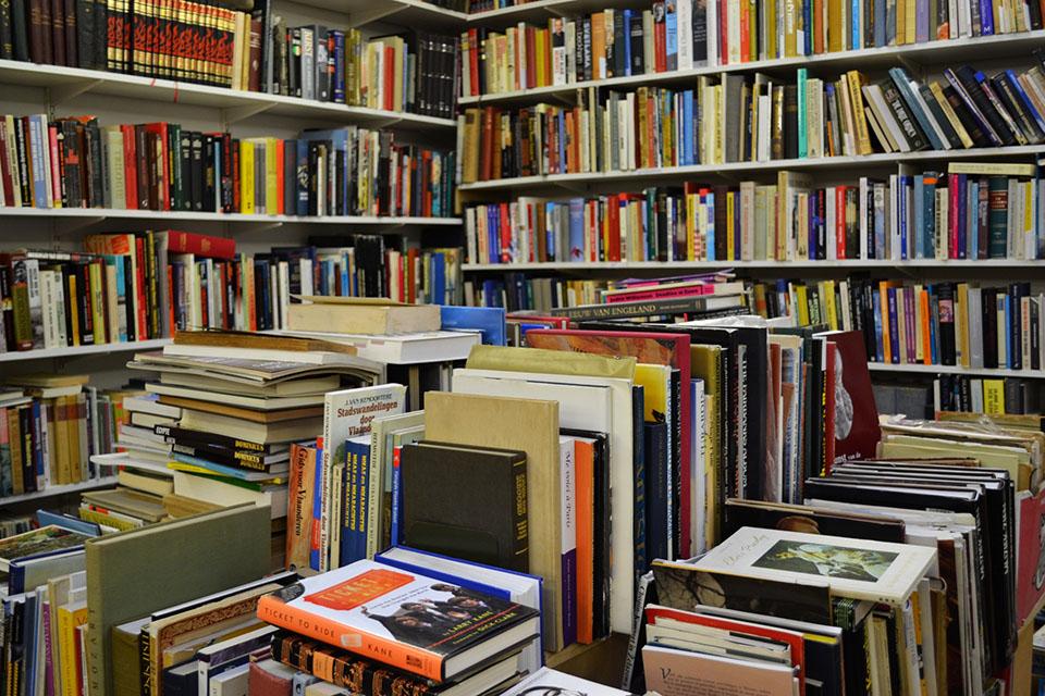 Books on table and shelves in a room.